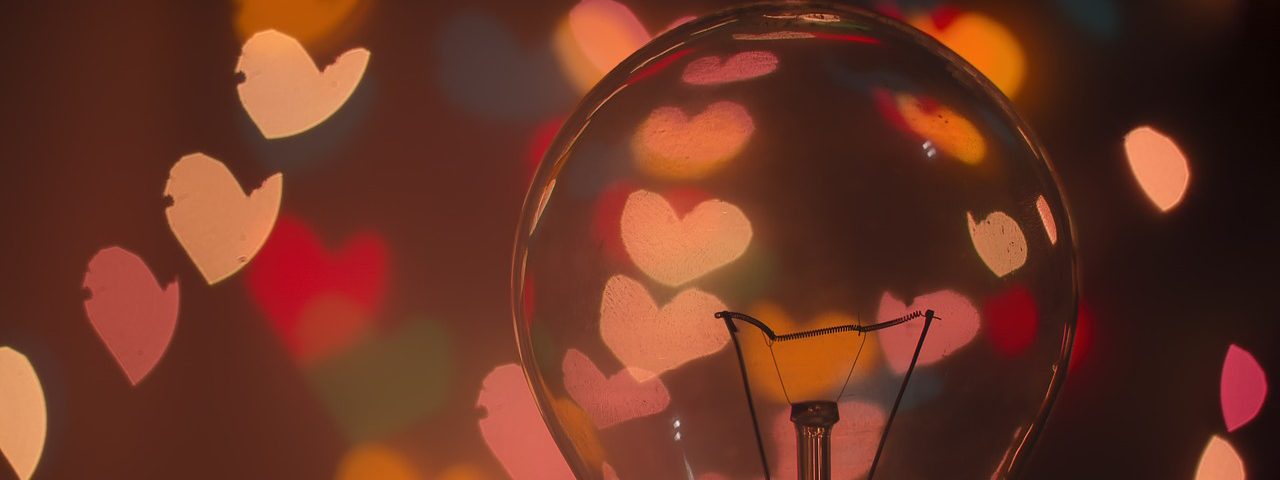 Image: A lightbulb casting heart-shaped red and orange hearts.