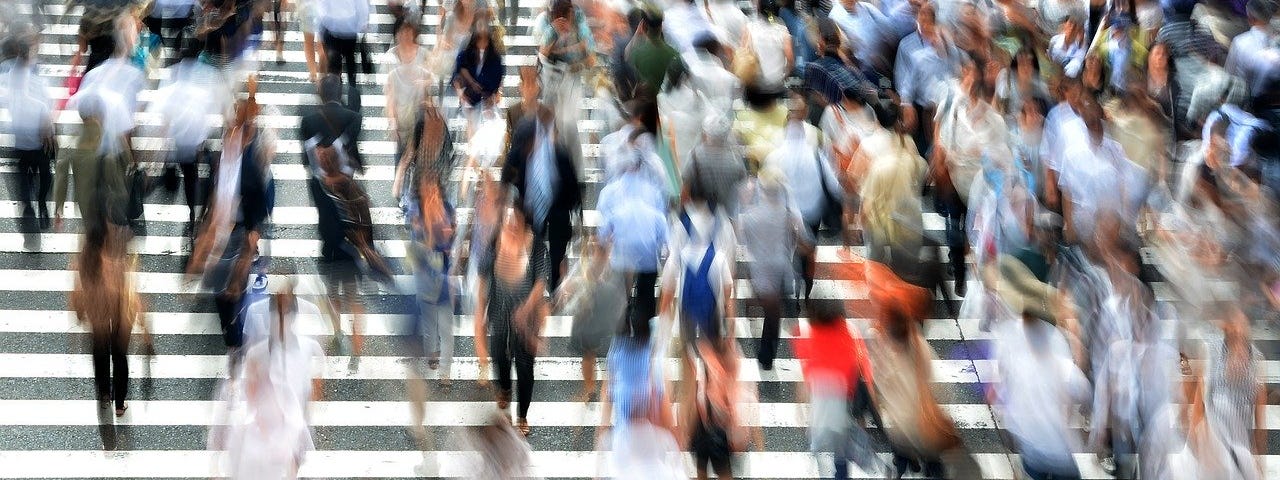 Crowds crossing the street in a busy crosswalk.