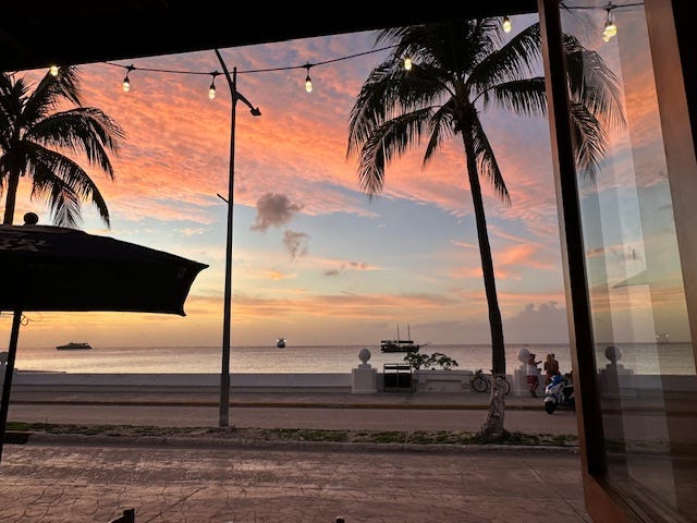 Sunset over the water as seen out a large window at a restaurant in Cozumel.