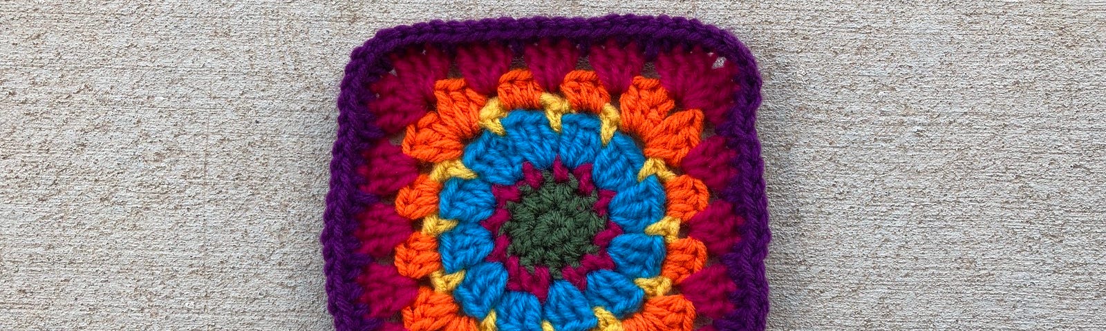 A multicolor crochet granny square that goes from circle to square