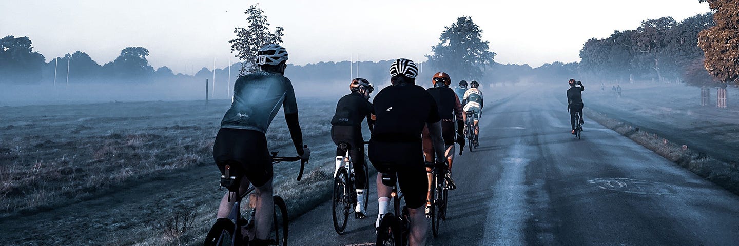 A group of cyclists in a misty park.