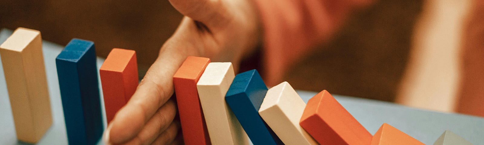 An image of a hand stopping a falling line of dominoes, symbolizing the power we possess to slow down, remain present, observe our thoughts, and redirect them to enhance our well-being