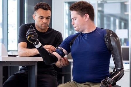 An engineer attaching bionic limbs to a wheelchair user.