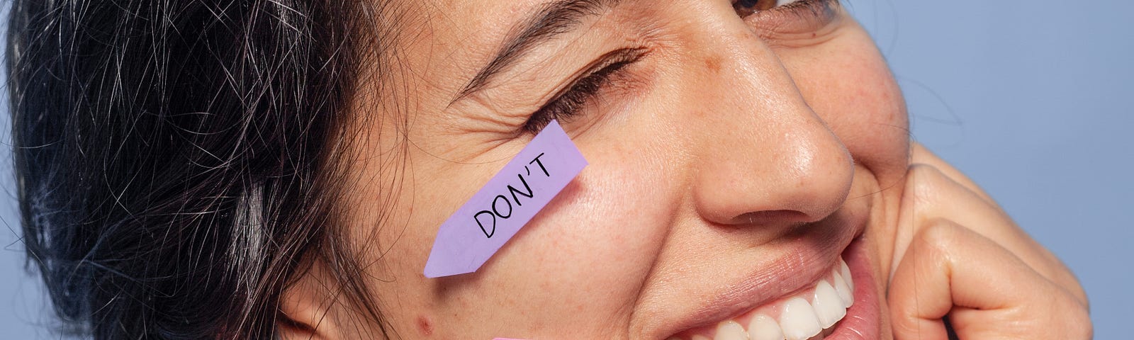 Woman with colored flags pointing to a blemish on her face, saying “Don’t pop”