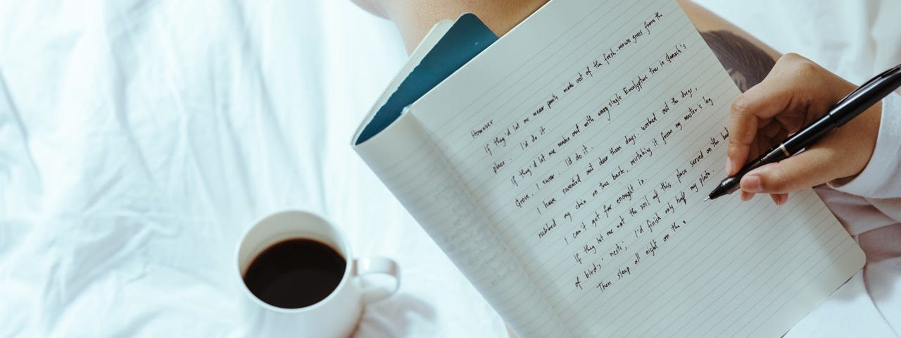 girl writing in bed on journal with coffee