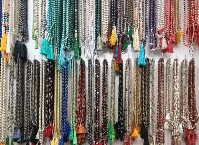 Display of thousands of strands of mala beads in all colors and types of stones hanging in a shop in Rishikesh, India