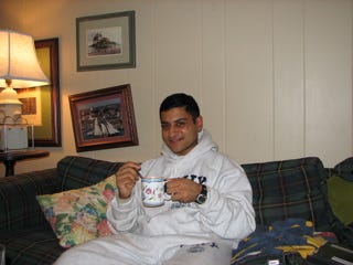 A man sitting on a couch with a up of coffee in his hand