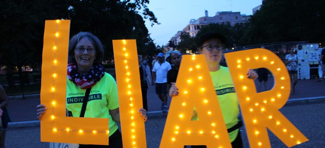 Women hold the letters L-I-A-R.