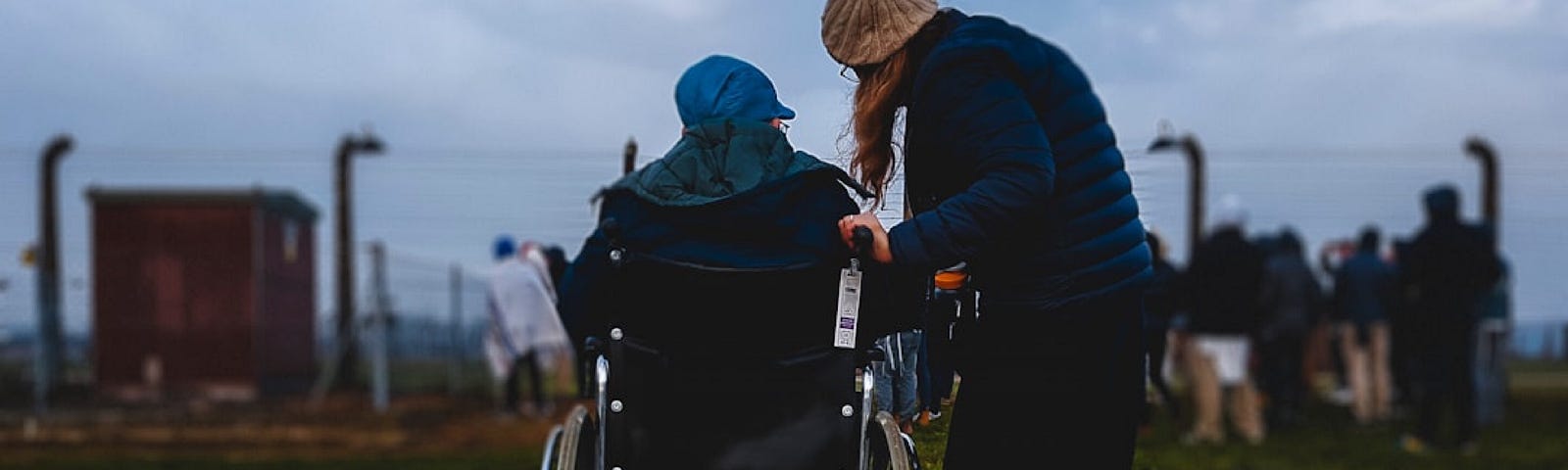 A care assistant supporting her client who is in a wheelchair out in the community.