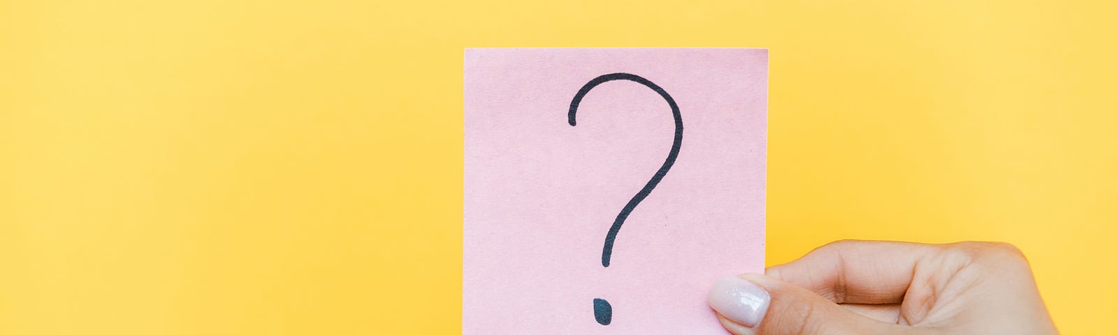 Cropped view of woman holding sticky note with question mark on orange