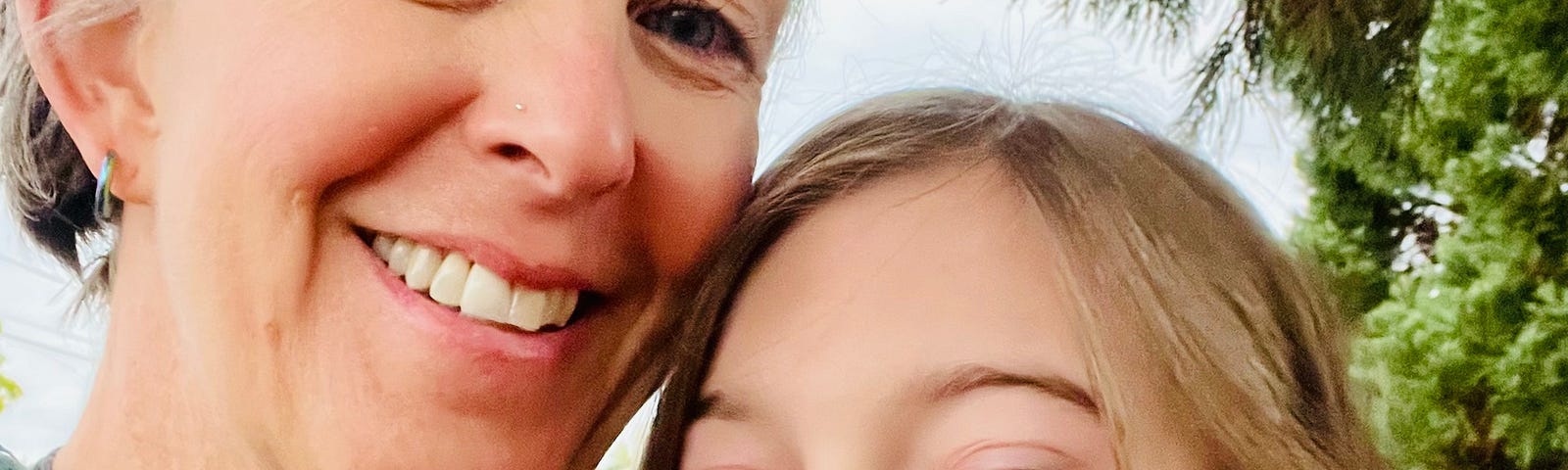 Photo of author and her daughter — both have blonde, medium-length hair and are smiling, daughter is 12 and sticking out her tongue playfully.
