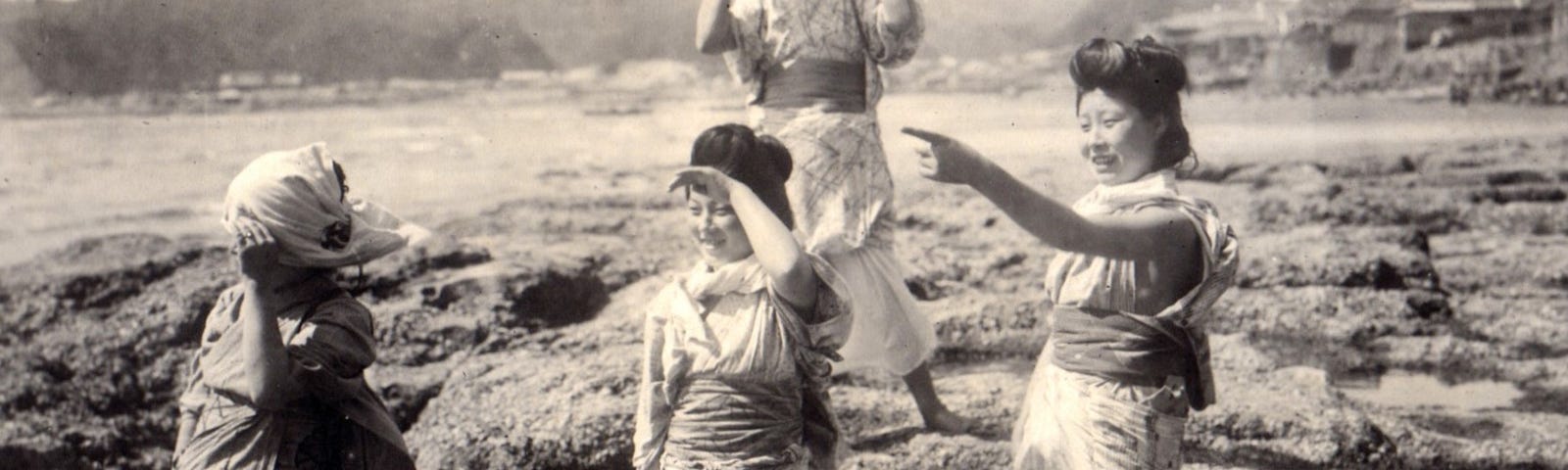 Women on a Japanese beach as the wind ruffles their clothes.