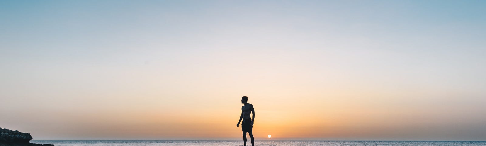 A man standing on a rock and staring into the sky