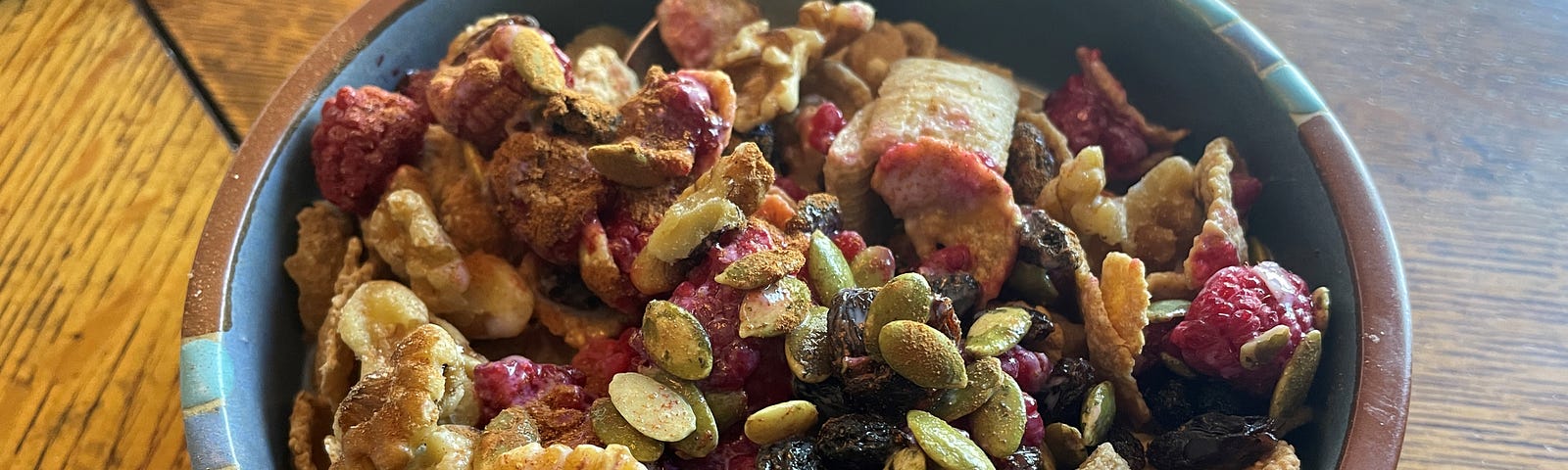 A bowl of whole-grain cereal topped with berries, walnuts, raisins, pumpkin seeds, and cinnamon.