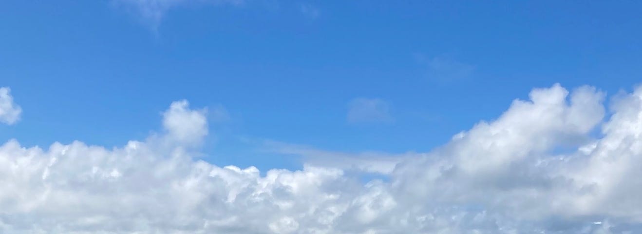 a photo of waves coming in at the beach, with a blue sky and white clouds above