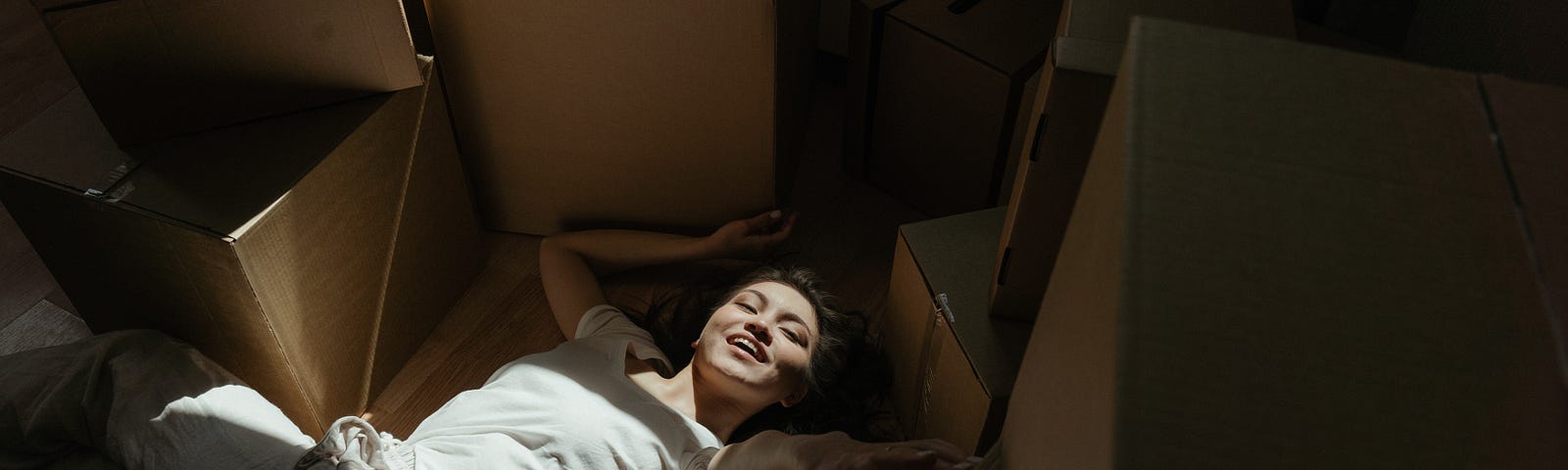 A woman lies blissfully among cardboard boxes.
