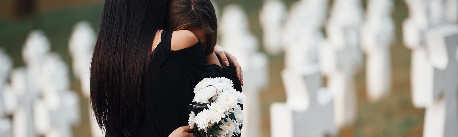 women embrace at cemetary