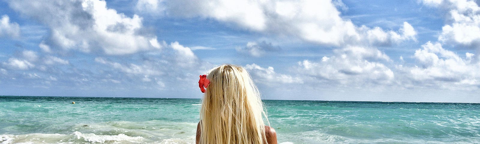Blonde woman in a swimsuit meditating in front of the ocean.