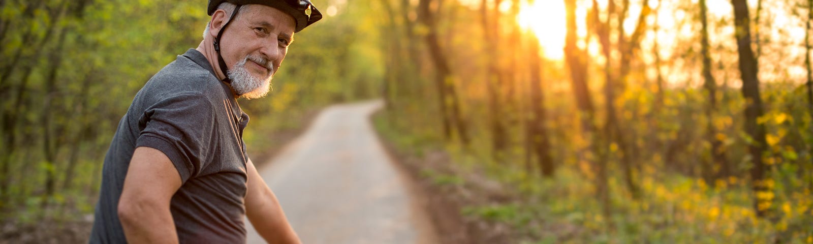 A senior man on his mountain bike outdoors in the forest.