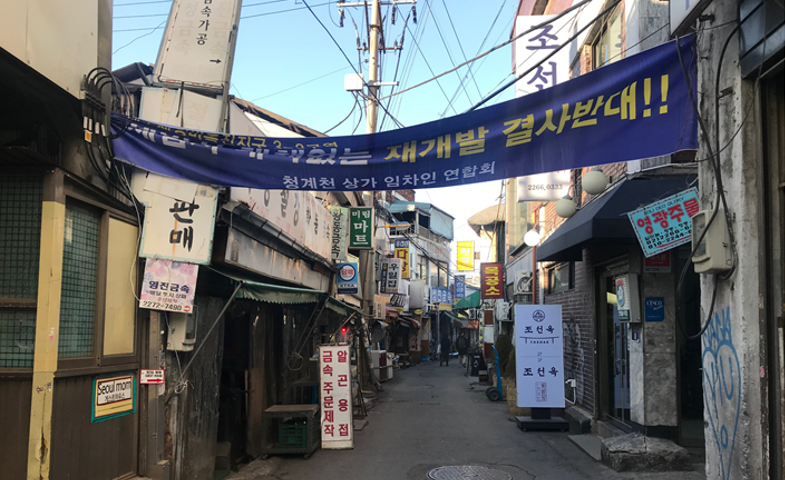 A small alley in the Euljiro-Chengyecheon manufacturing district with an anti-redevelopment banner hanging across the street.