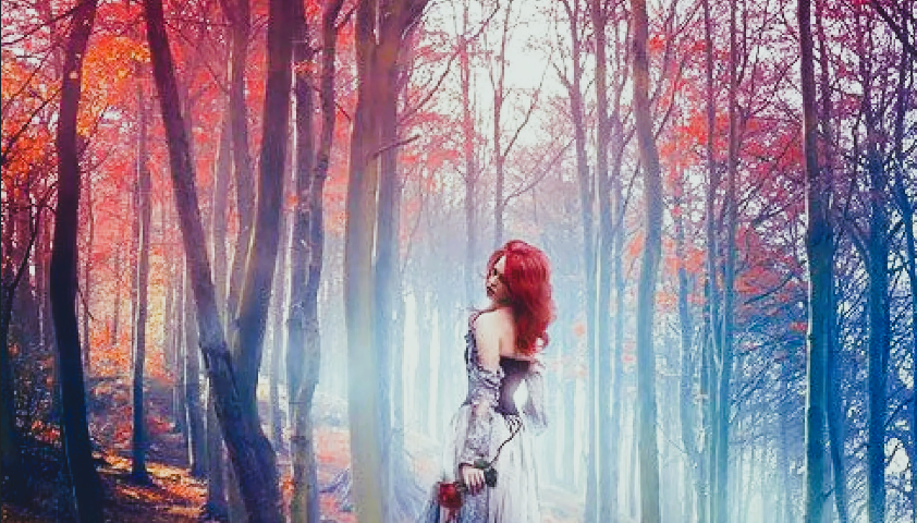 A woman walking through the woods wearing a long pretty dress