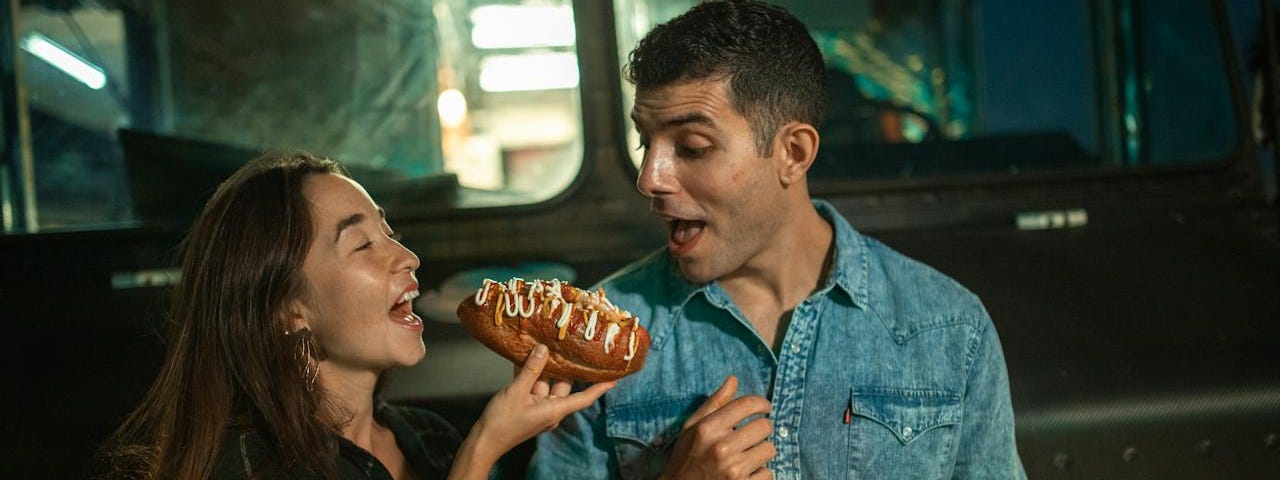 man and woman eating American food and laughing.