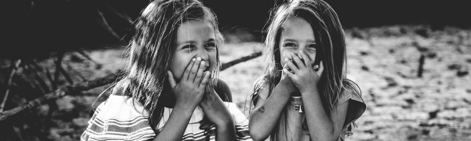 Black and white photo of two young girls gigglling.
