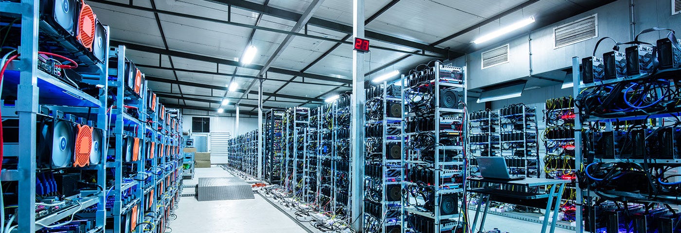 A corridor of a server farm lined with tall racks of computers used for mining cryptocurrency.