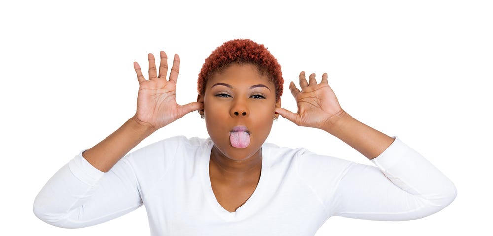 Closeup portrait of funny, angry, young, childish rude bully Black woman sticking tongue out at you camera gesture, isolated on white background. Negative emotions facial expression feelings.