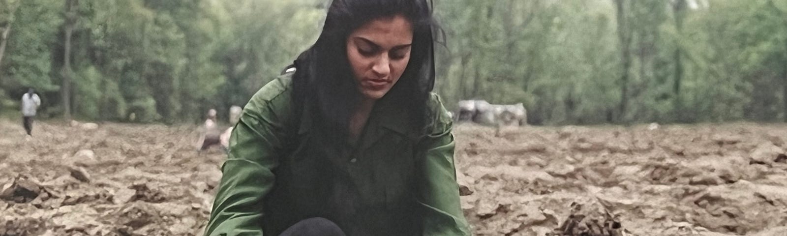 Photo of the author in her early 20s sifting through dirt at Crater of Diamonds National Park in Arkansas. There is a line of trees in the background.