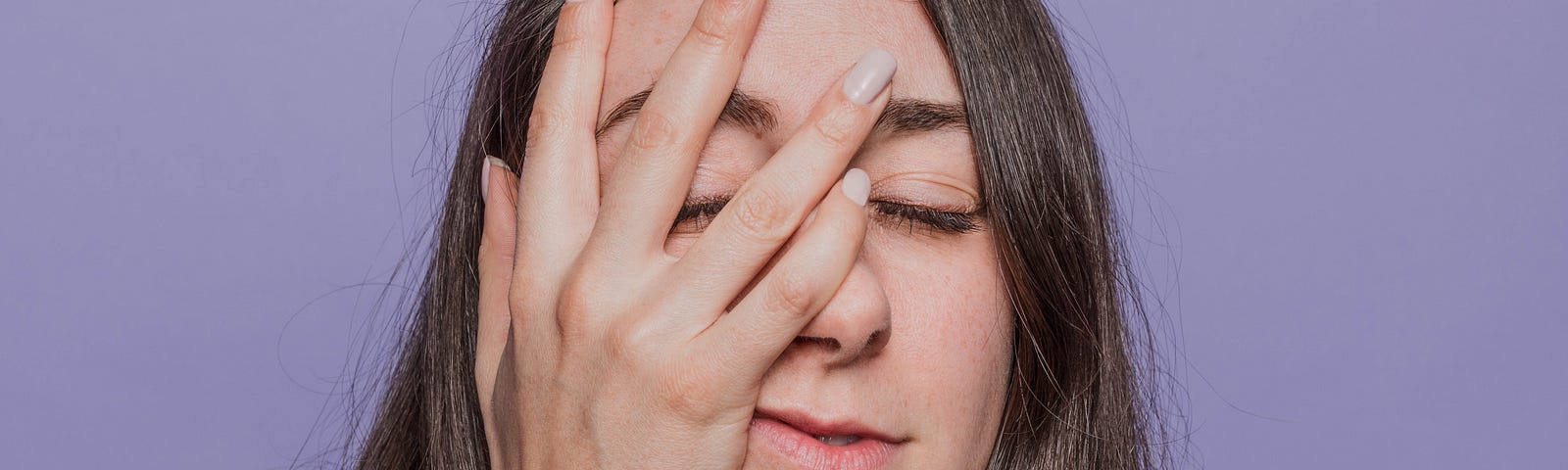 Woman with her hand on her face, frustrated with the skin purging period that comes with trying new products