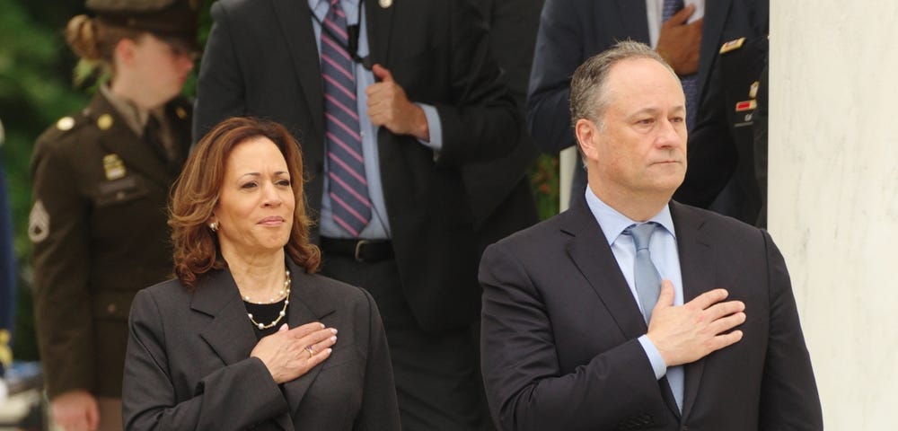 Vice-President Kamala Harris stands next to her husband, Second Gentleman Doug Emhoff, with their hands over their hearts, pledging allegiance to the flag.