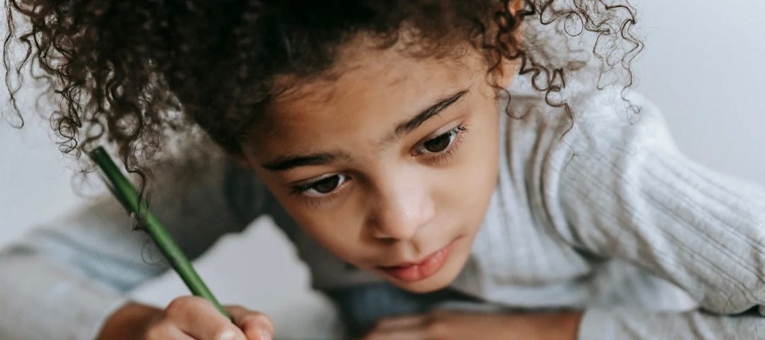 A little girl writing on a book