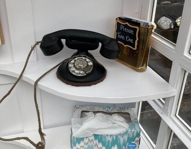 Antique rotary phone inside a Wind Phone, along with a box of tissues.