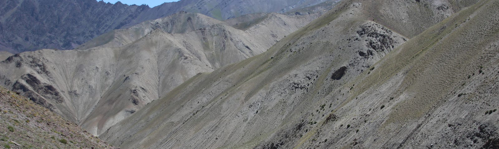 A group of pack horses on a dusty path in a dry, treeless mountain range