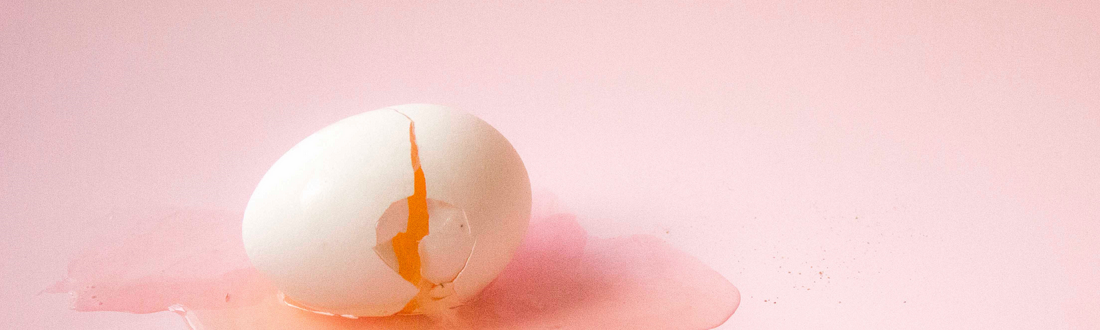 White cracked egg with pink background