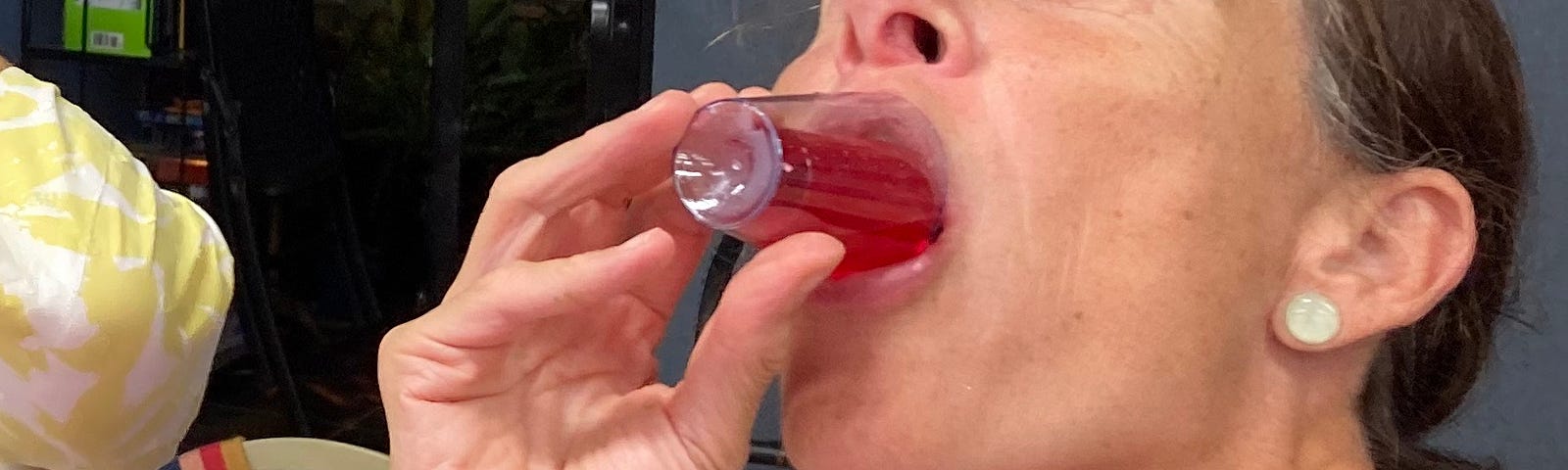 Adult woman drinking a red Jell-O shot