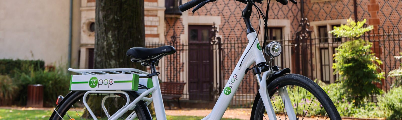 A Pi-Pop electric bike parked near a building on a lawn.