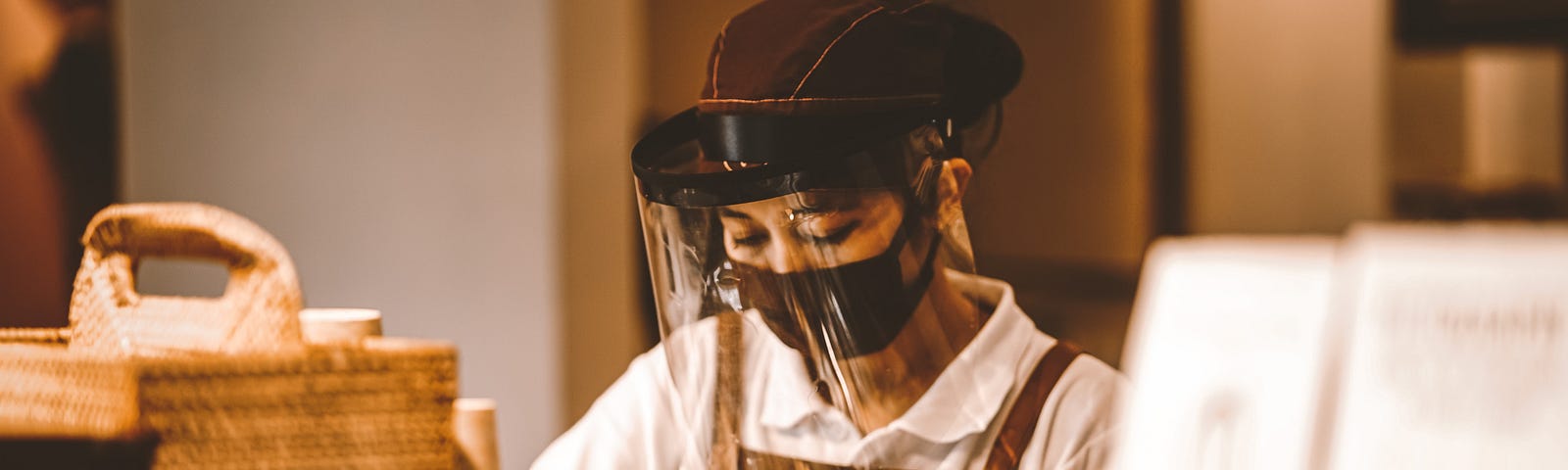 Image of a shop worker wearing a mask and face shield while working