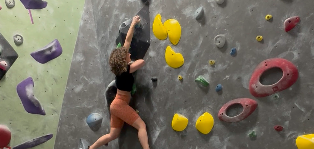 Woman rock climbing at a bouldering gym