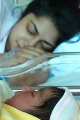 An Indian woman, the writer of the article sleeps next to her newborn