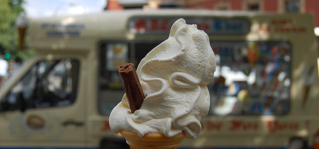Person holding 99 flake ice cream outside an ice cream van.