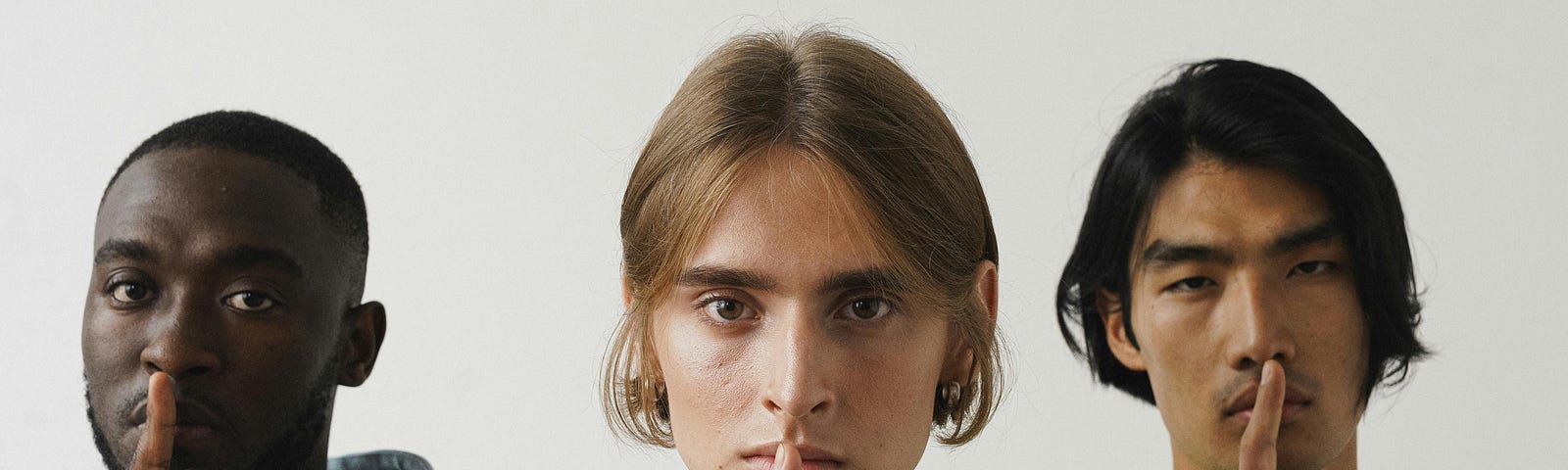 Three men hold their fingers to their lips in classic “shush” pose.