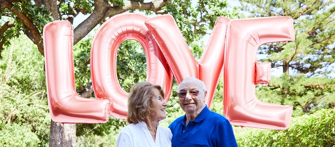 Image of the author’s grandparents standing under a sign that says “love”