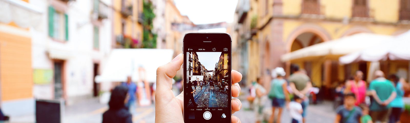 man holding a phone with the camera facing a busy old street