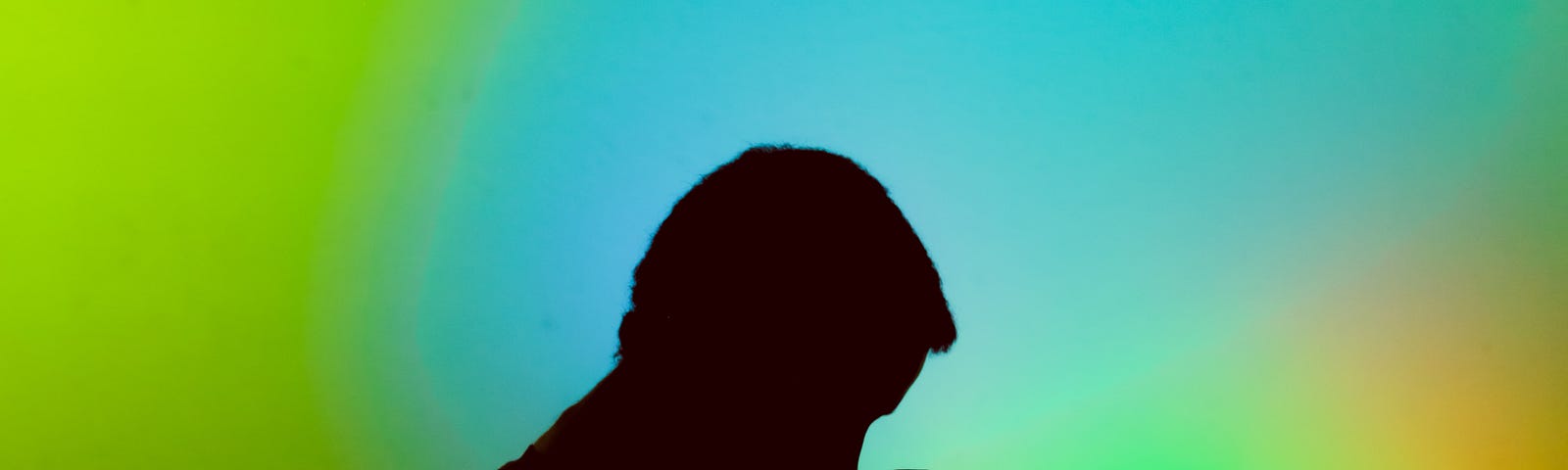 Silhouette of man thinking with bright, abstract colors in the background.