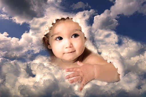 An infant’s face surrounded by fluffy white clouds.