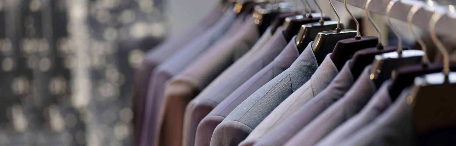 Several suits in slightly varying shades of gray hang on a rack.