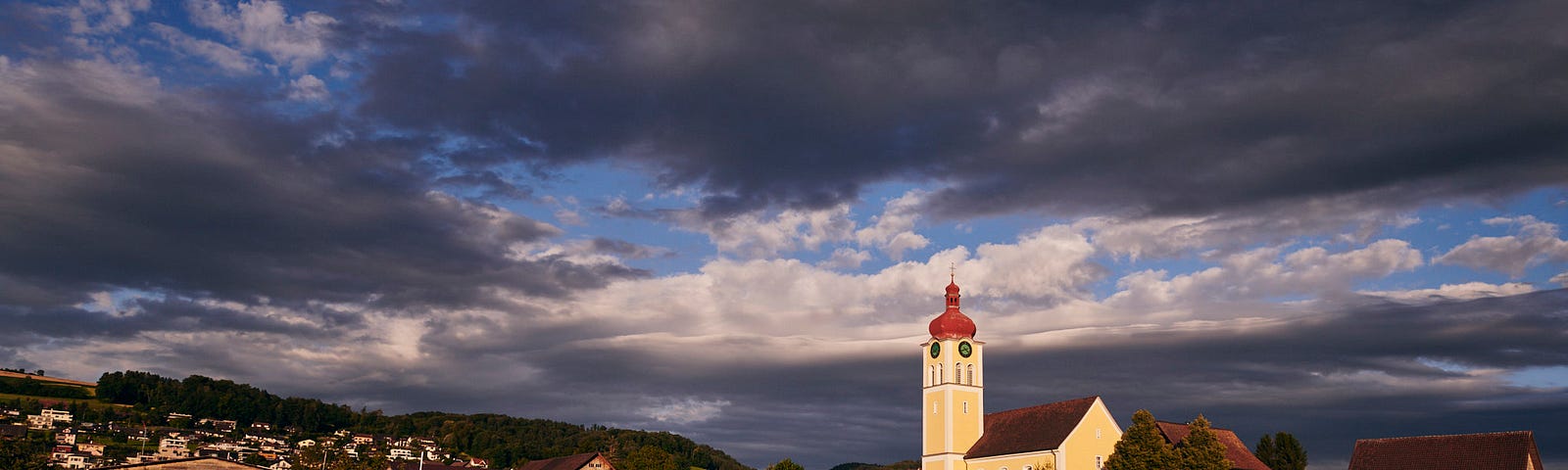 A village with a church and a field in the foreground.