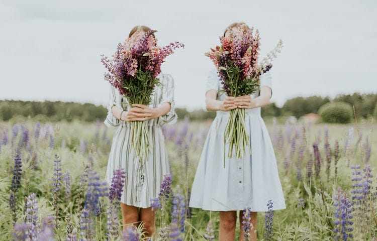 two teens in a field of wildflowers with bouquets of wildflowers covering their faces, practical parenting tips